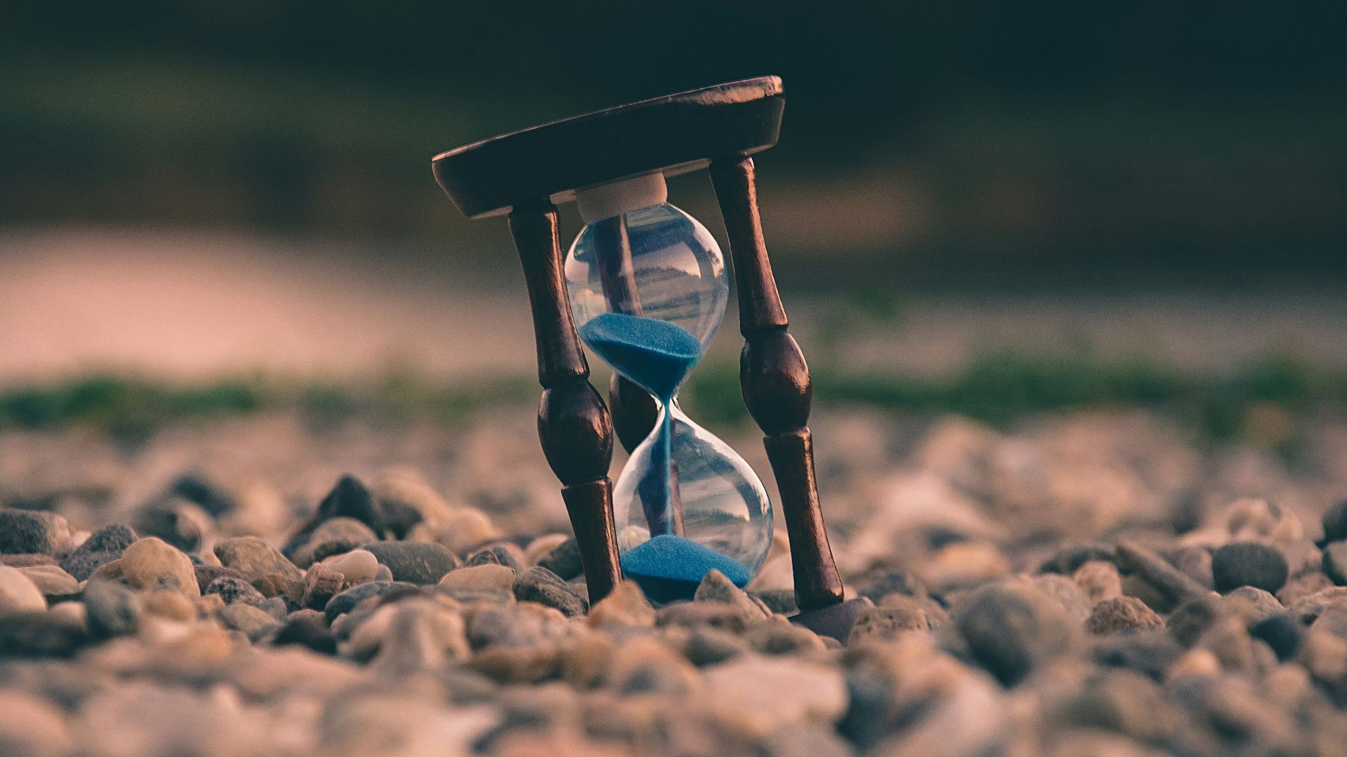 selective focus photo of brown and blue hourglass on stones