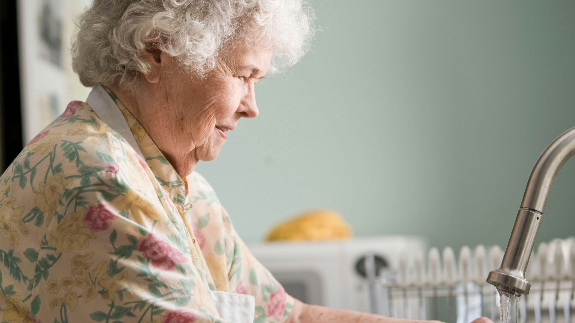 woman in yellow and green floral shirt holding white ceramic mug