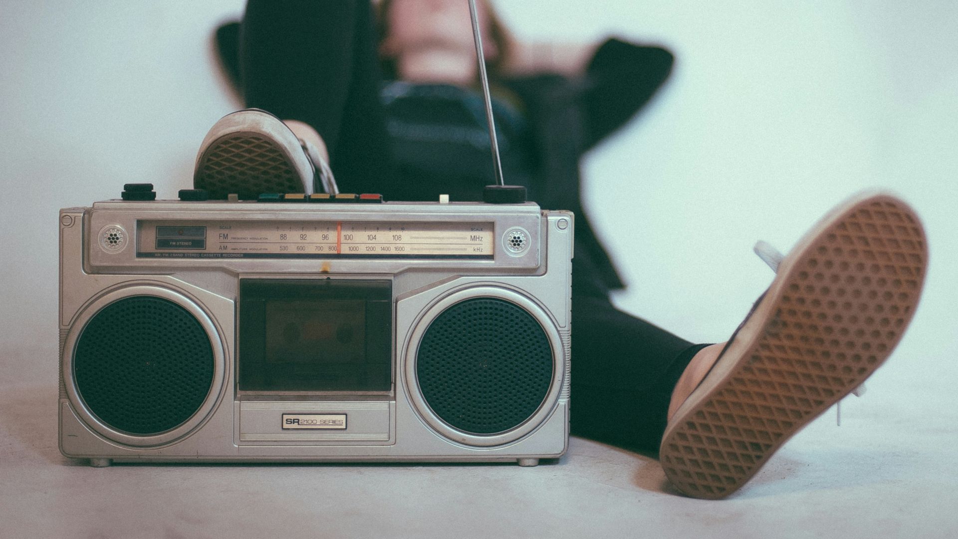 woman laying on bed near gray radio