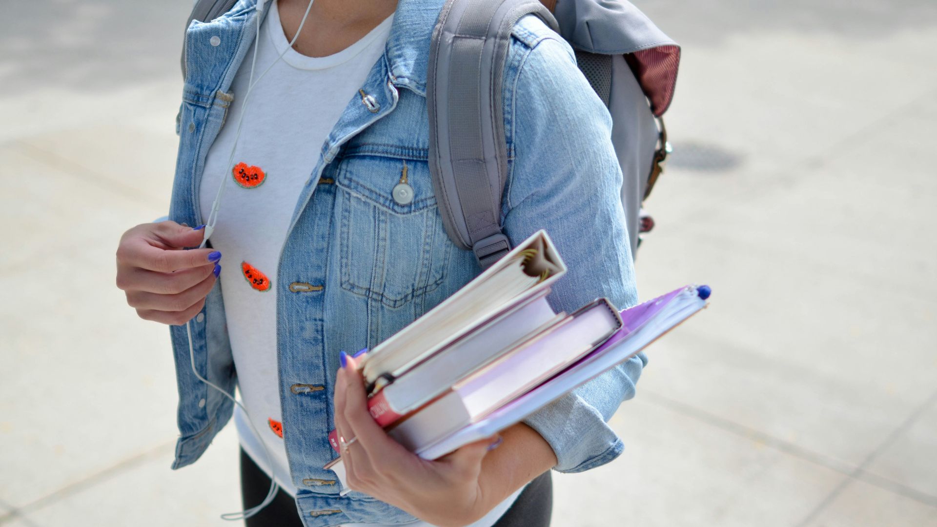 woman wearing blue denim jacket holding book