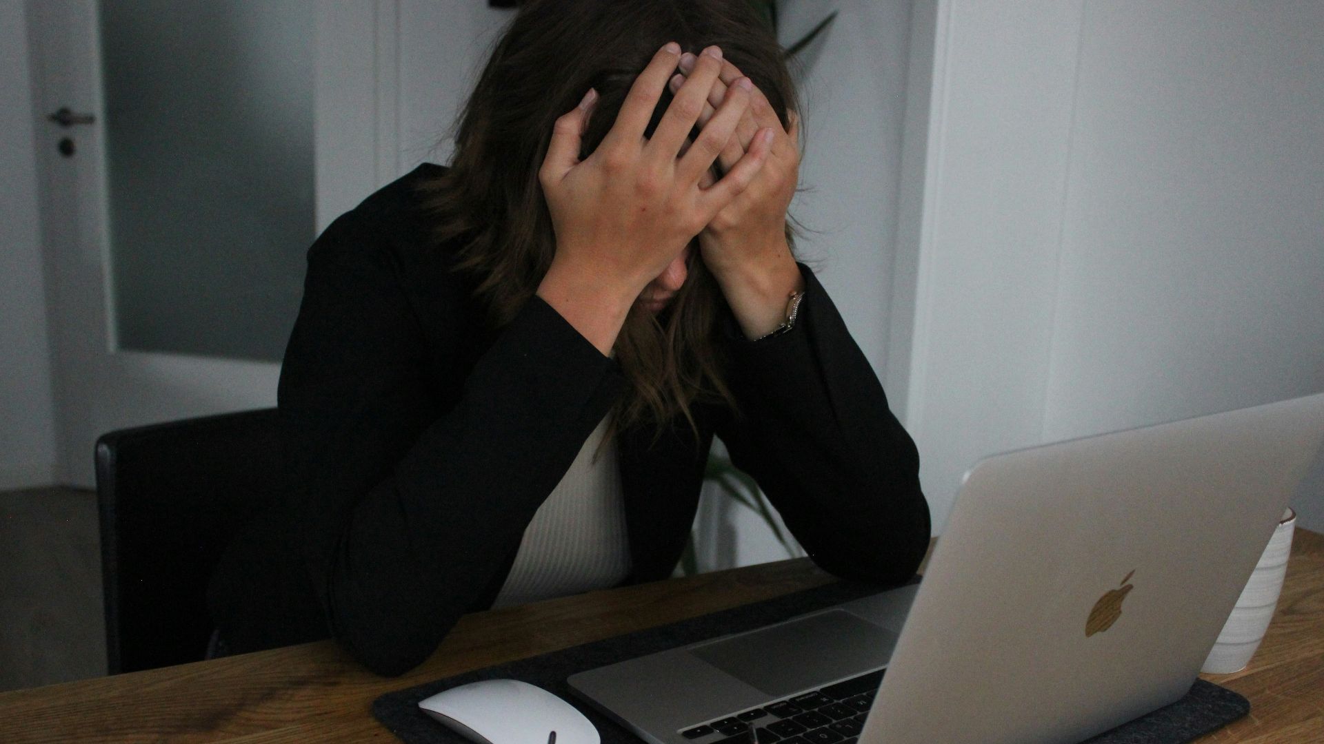 a woman covering her face while looking at a laptop