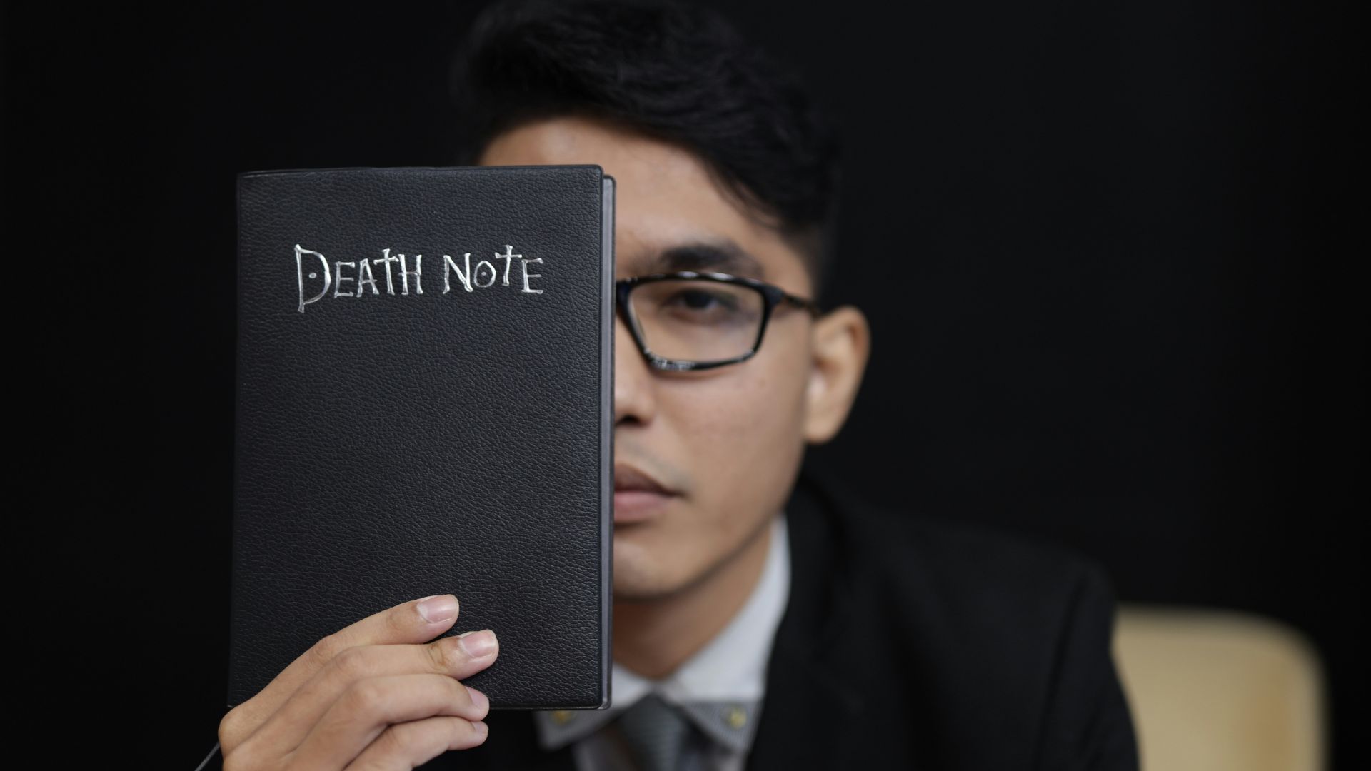 man in black suit holding black book