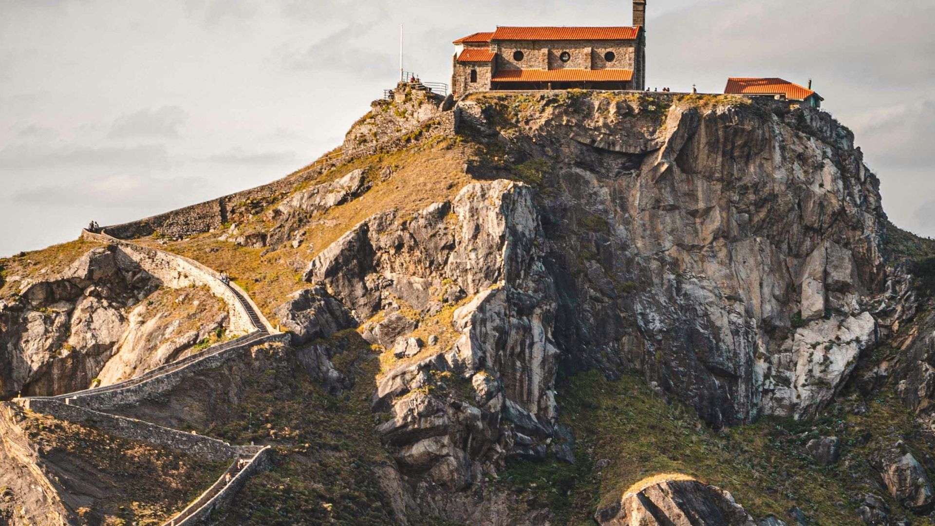 brown concrete building on cliff near body of water during daytime