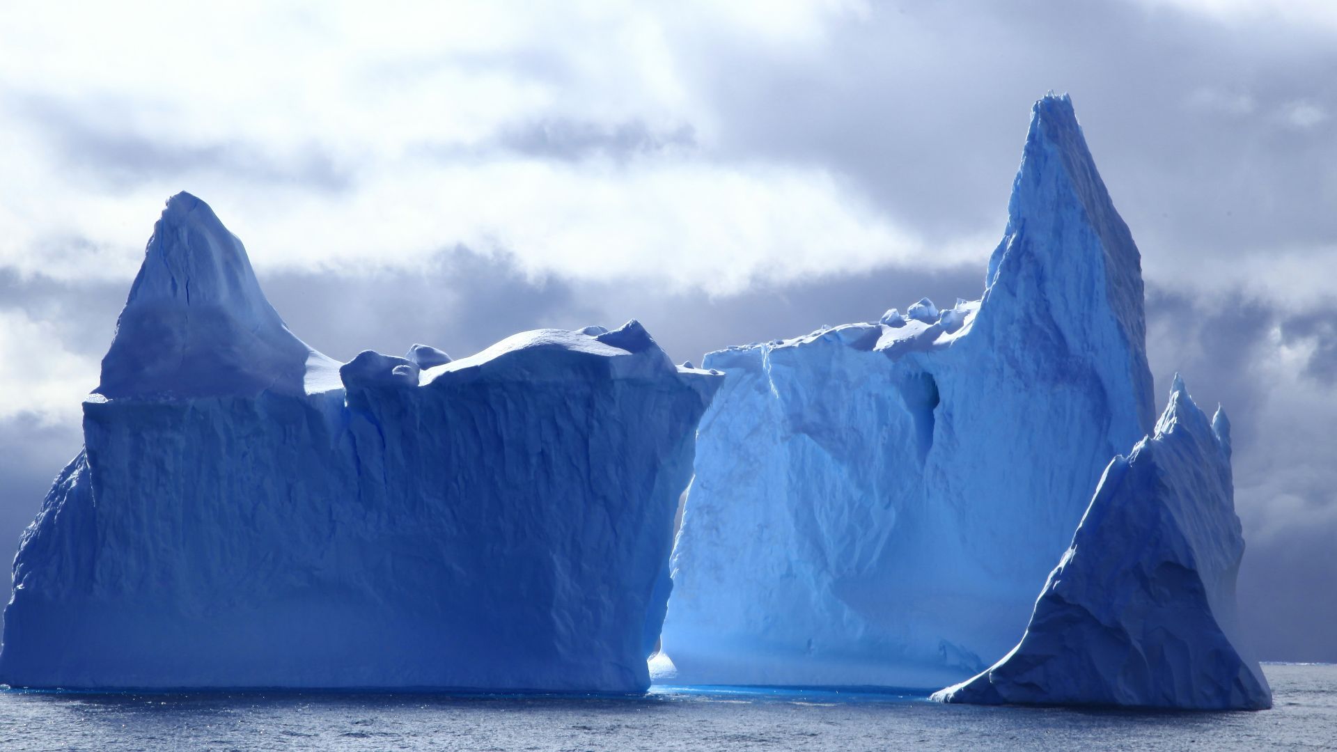 two icebergs under cloudy sky at daytime