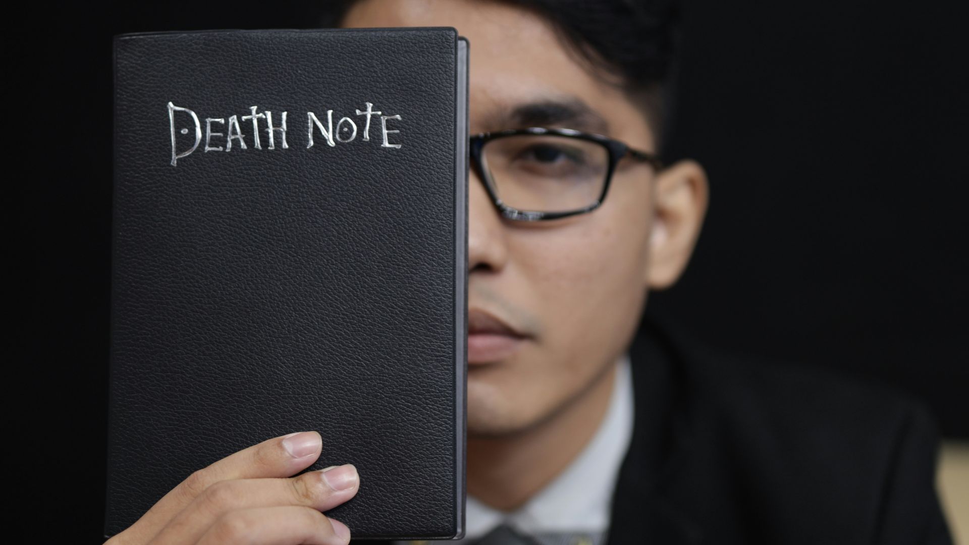 man in black suit holding black book