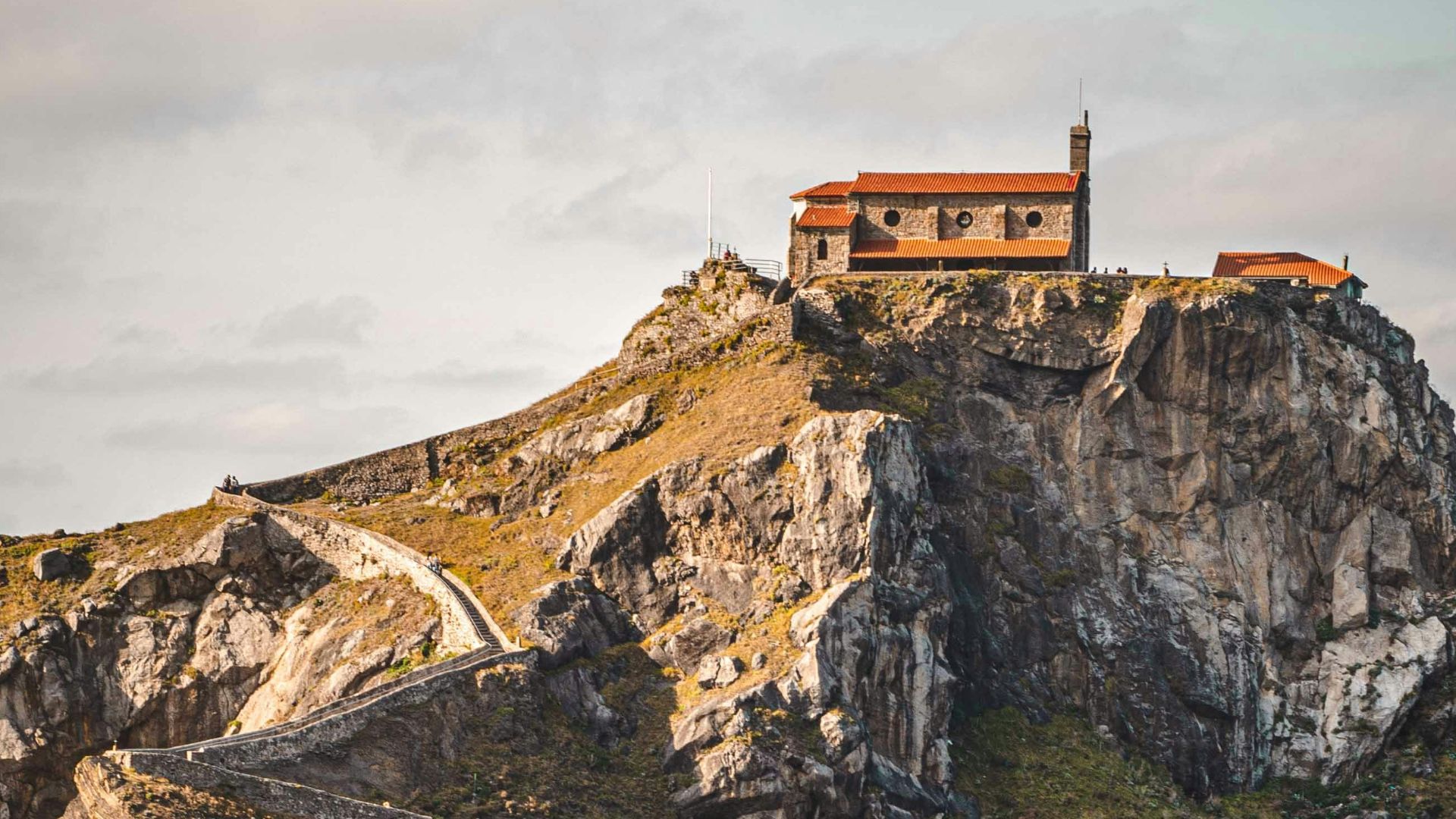 brown concrete building on cliff near body of water during daytime