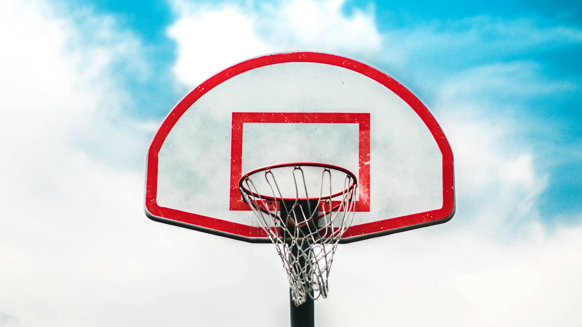 red and black basketball hoop under cloudy sky