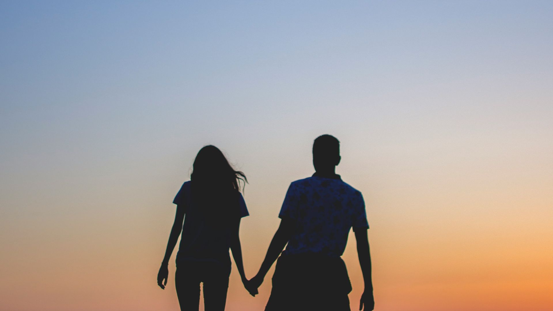 man and woman holding hands in silhouette photography