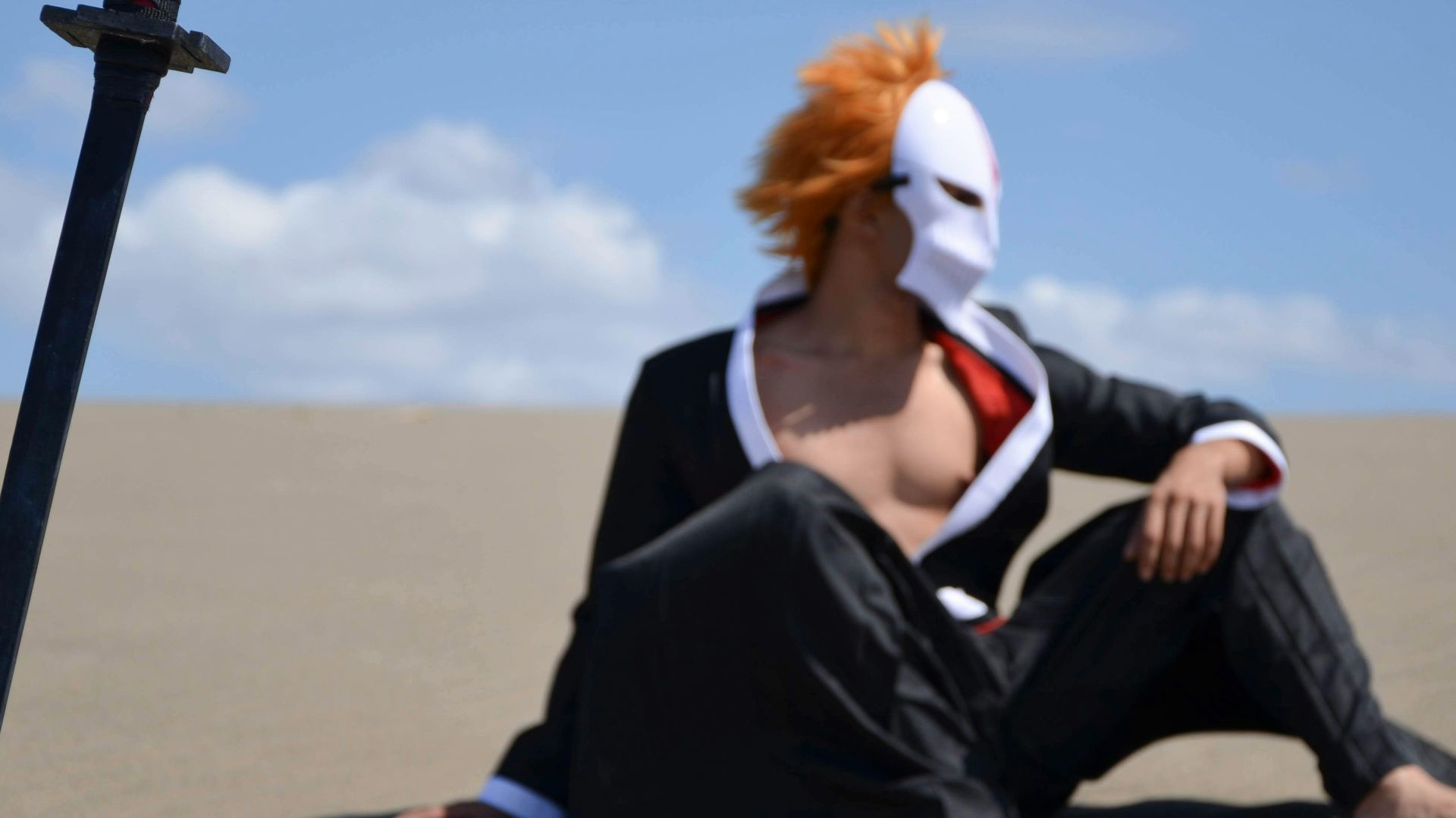 a person sitting in the sand with a mask on