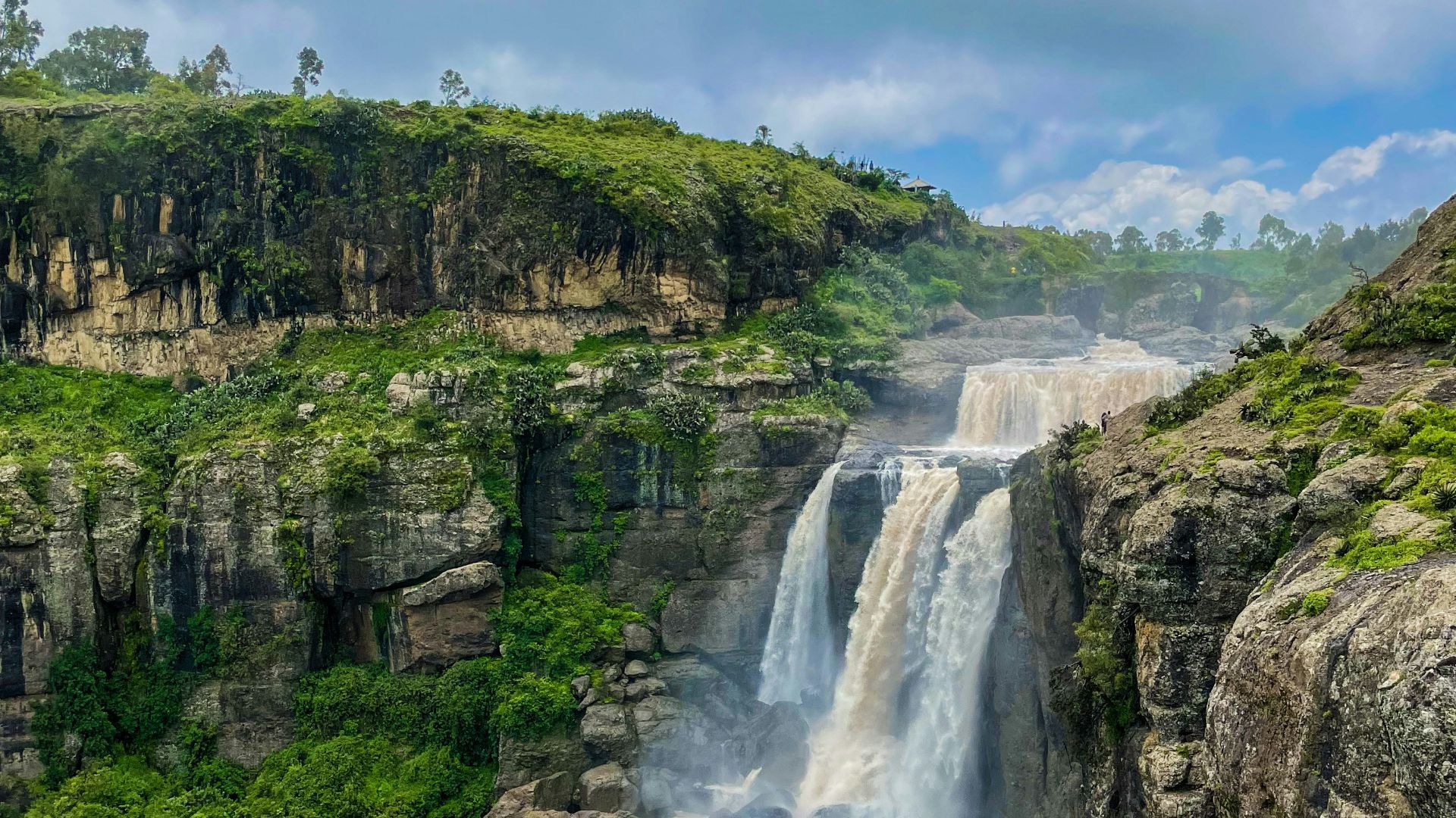 a waterfall in the middle of a lush green valley