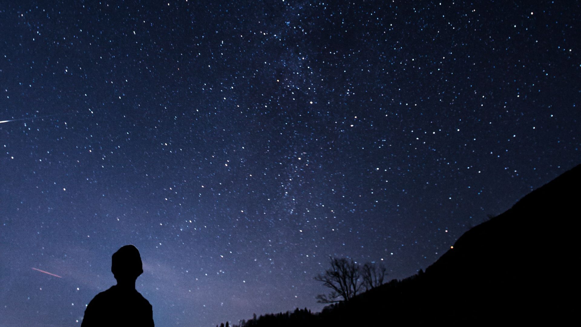 silhouette of man looking at milky way