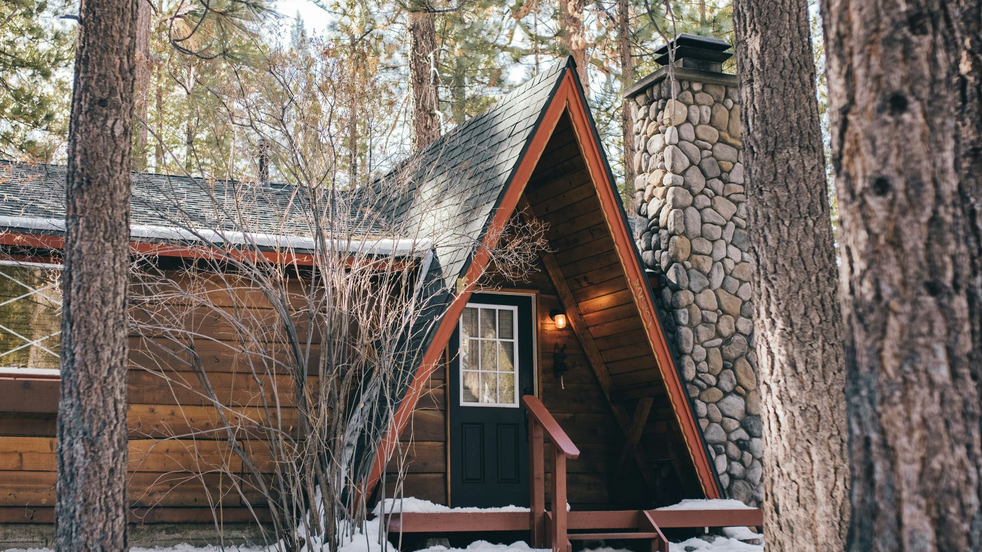 brown wooden house in the middle of the forest covered with snow