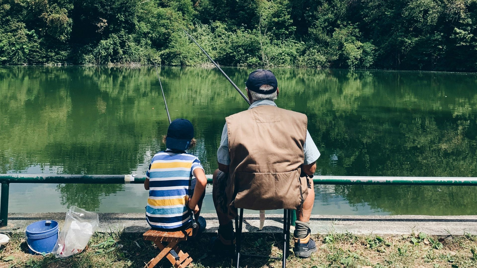man in black shirt sitting on chair near lake during daytime