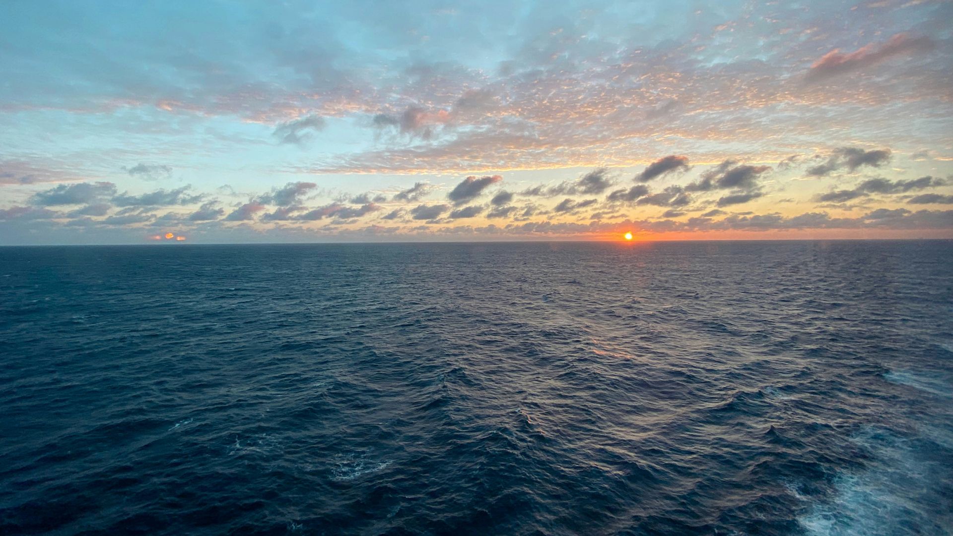 the sun is setting over the ocean as seen from a boat