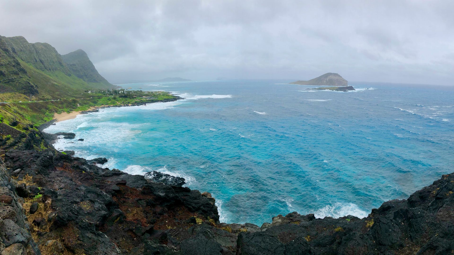 body of water near mountain under cloudy sky during daytime