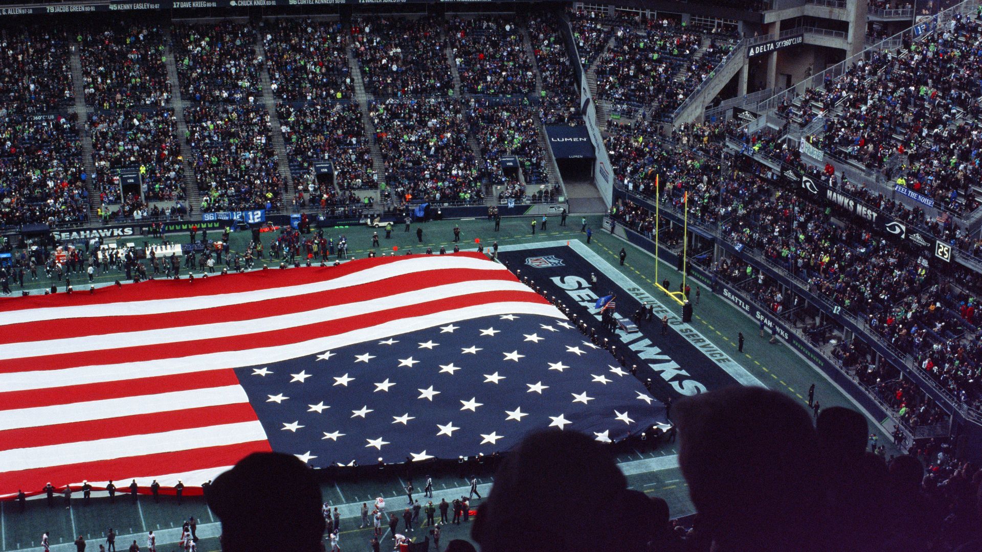 a large american flag is displayed in a stadium