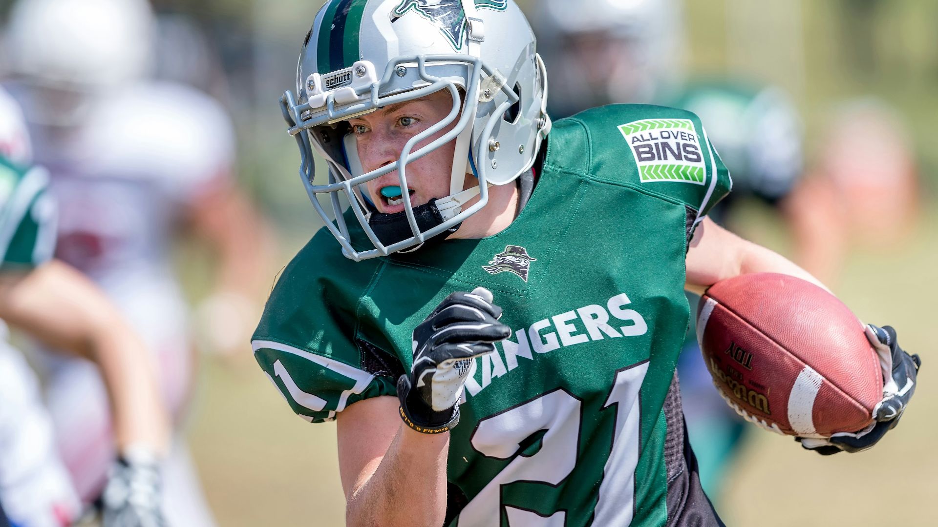 woman holding football while running near players
