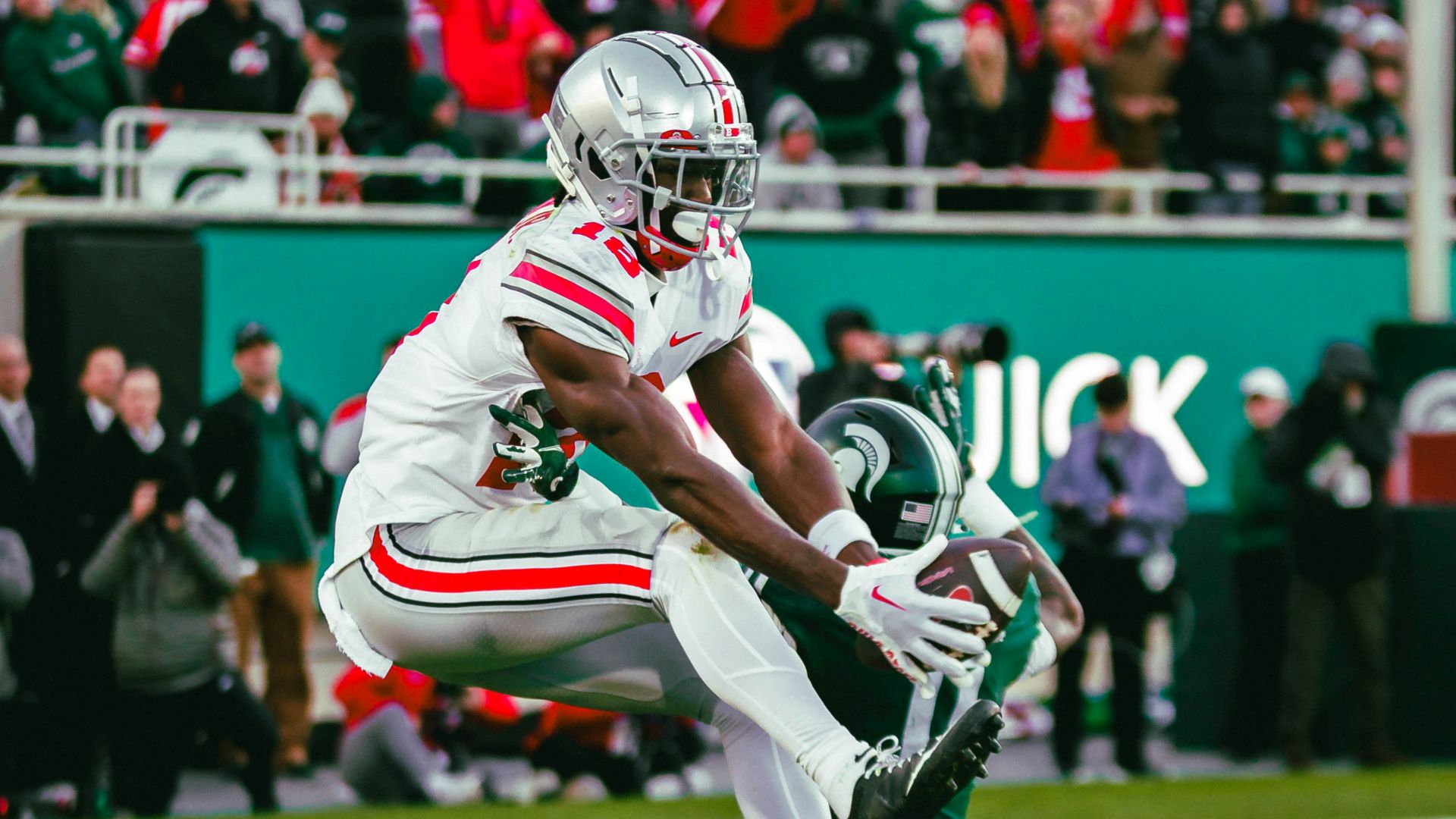 A football player running with a football on a field