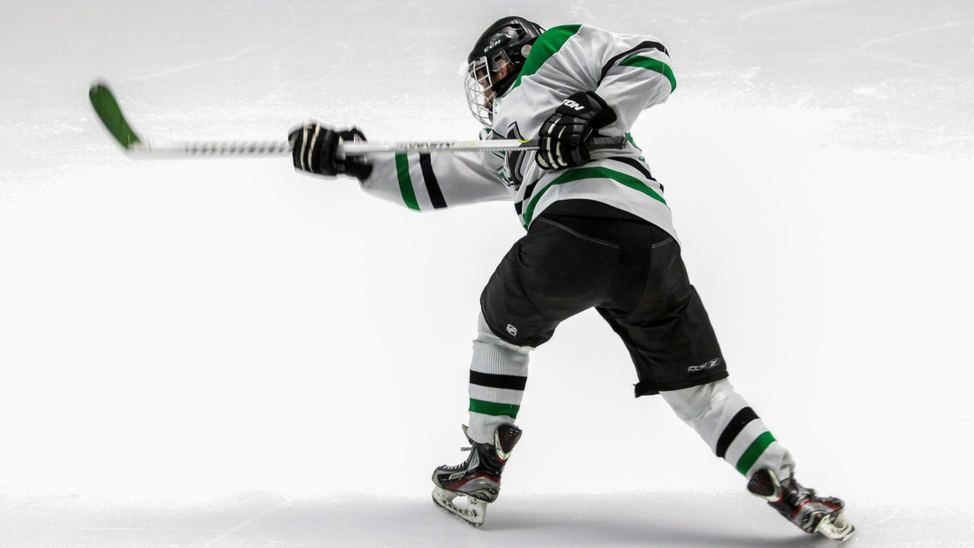 man wearing green and white ice hockey jersey while playing