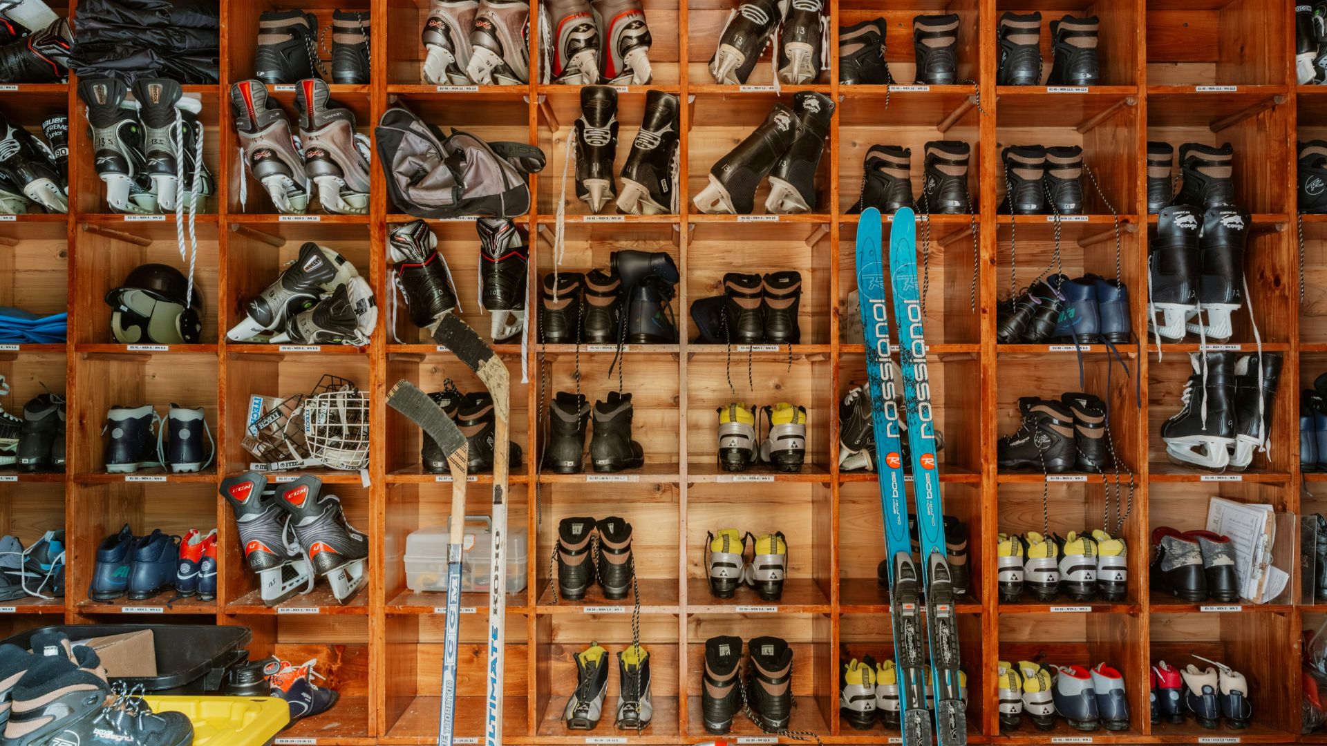 Ski boots and equipment organized on a wall.