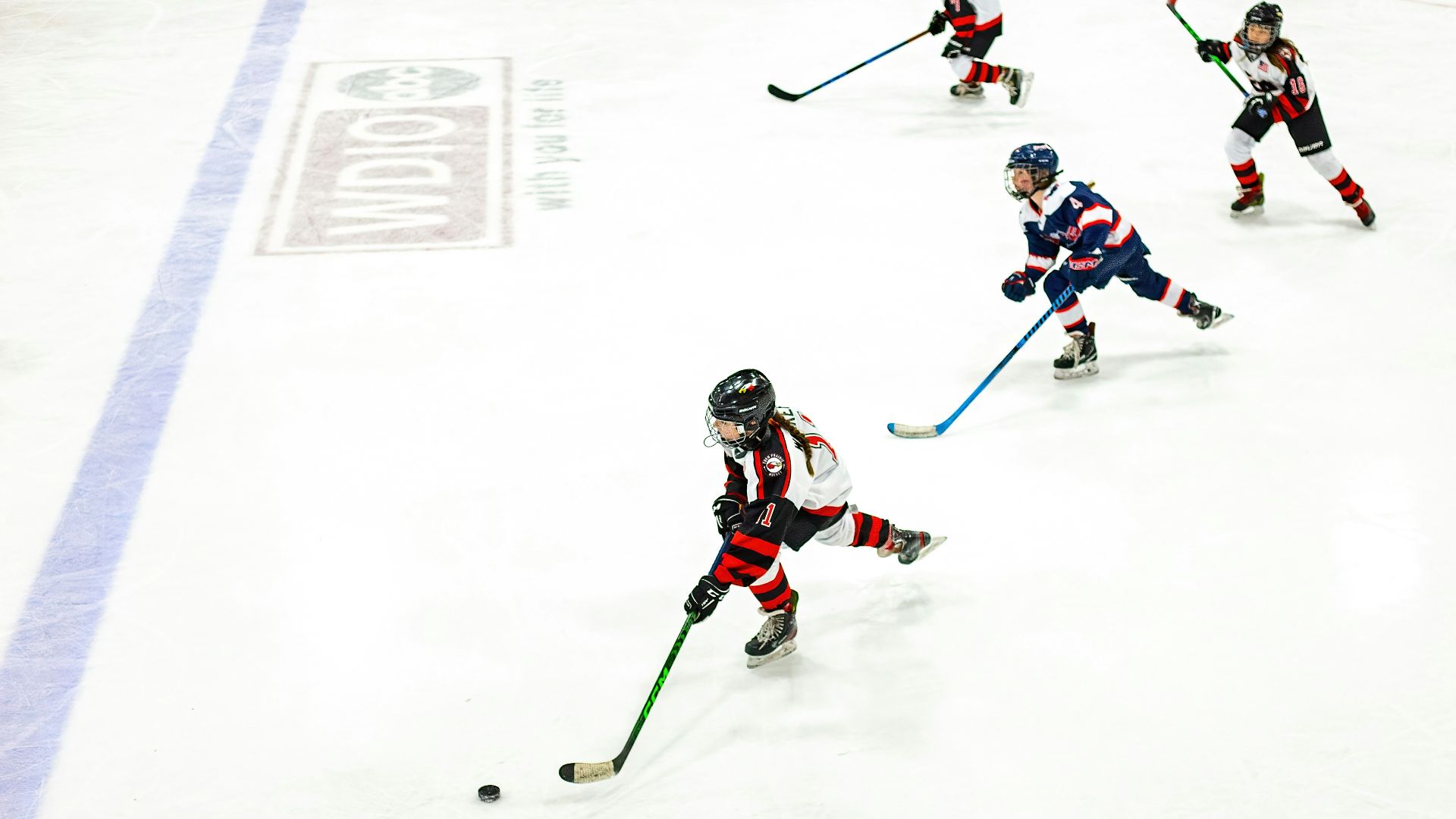 a group of young children playing a game of ice hockey
