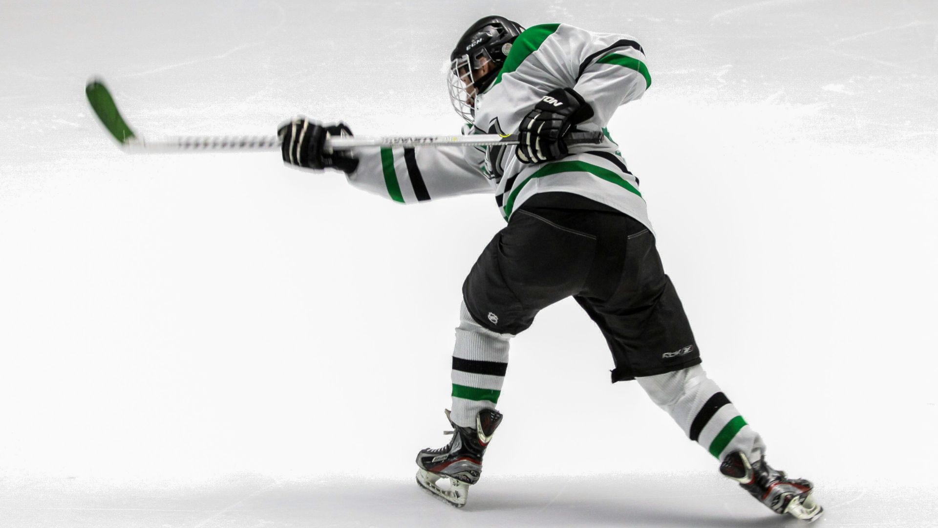 man wearing green and white ice hockey jersey while playing
