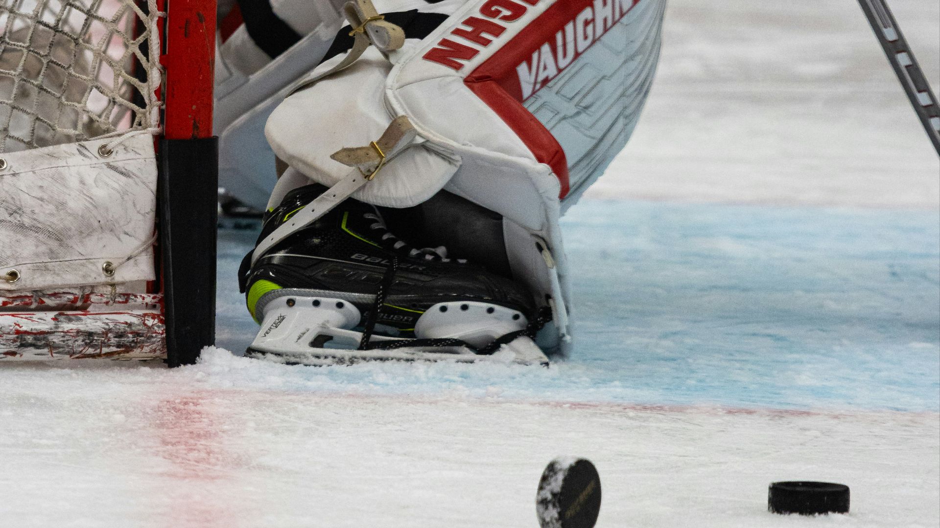 a hockey goalie kneels in front of the net
