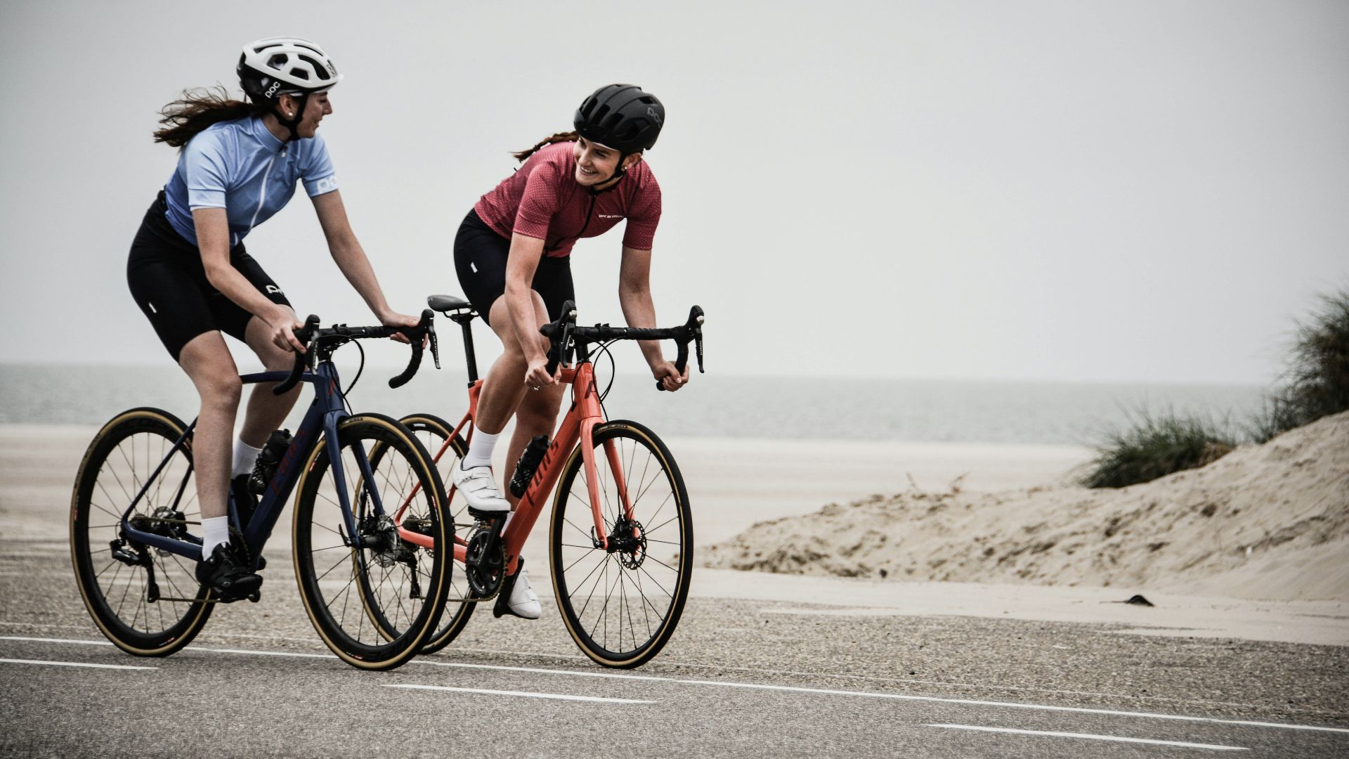 man and woman riding road bikes at the road near shore