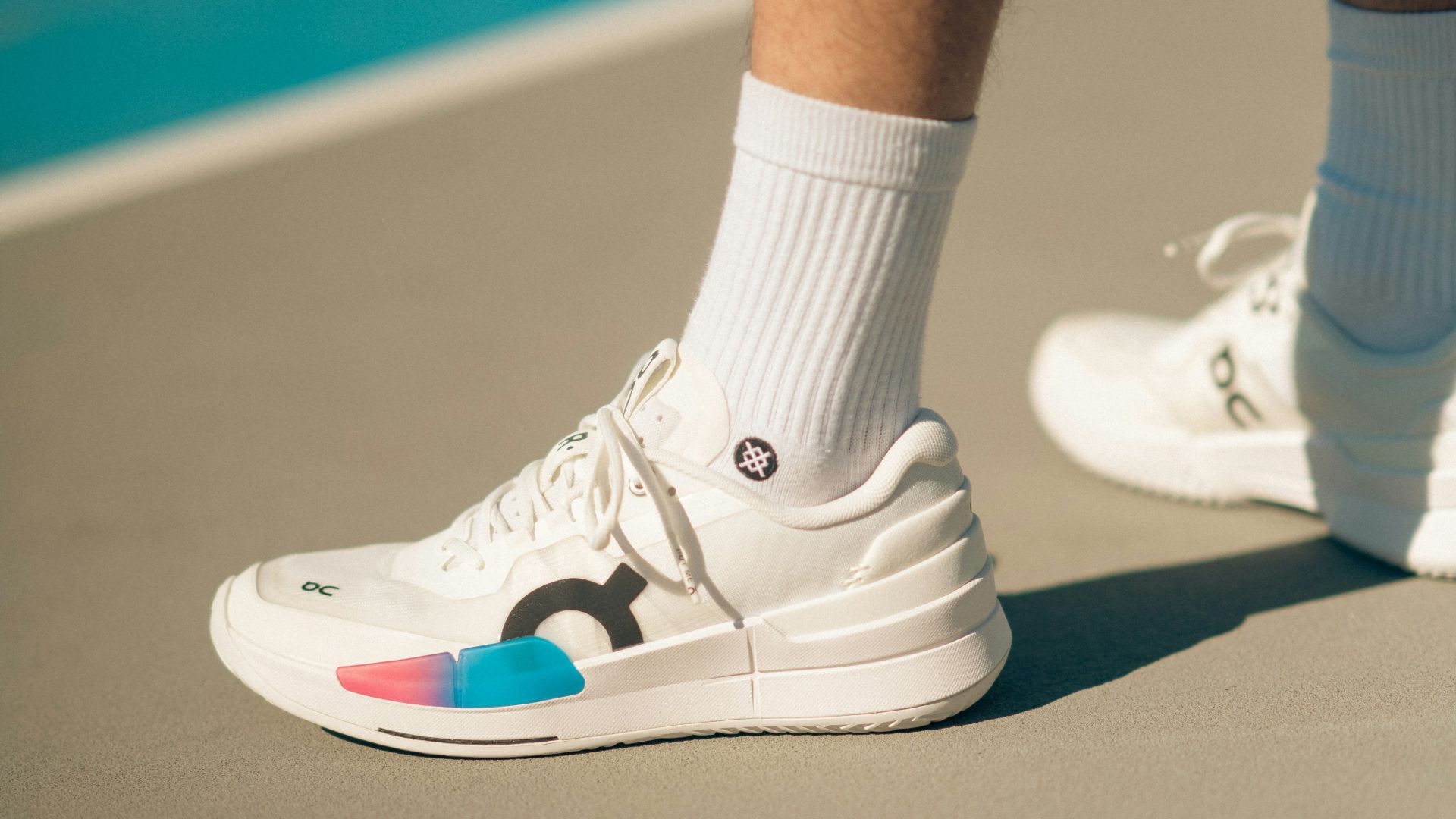 A person standing on a tennis court wearing white tennis shoes