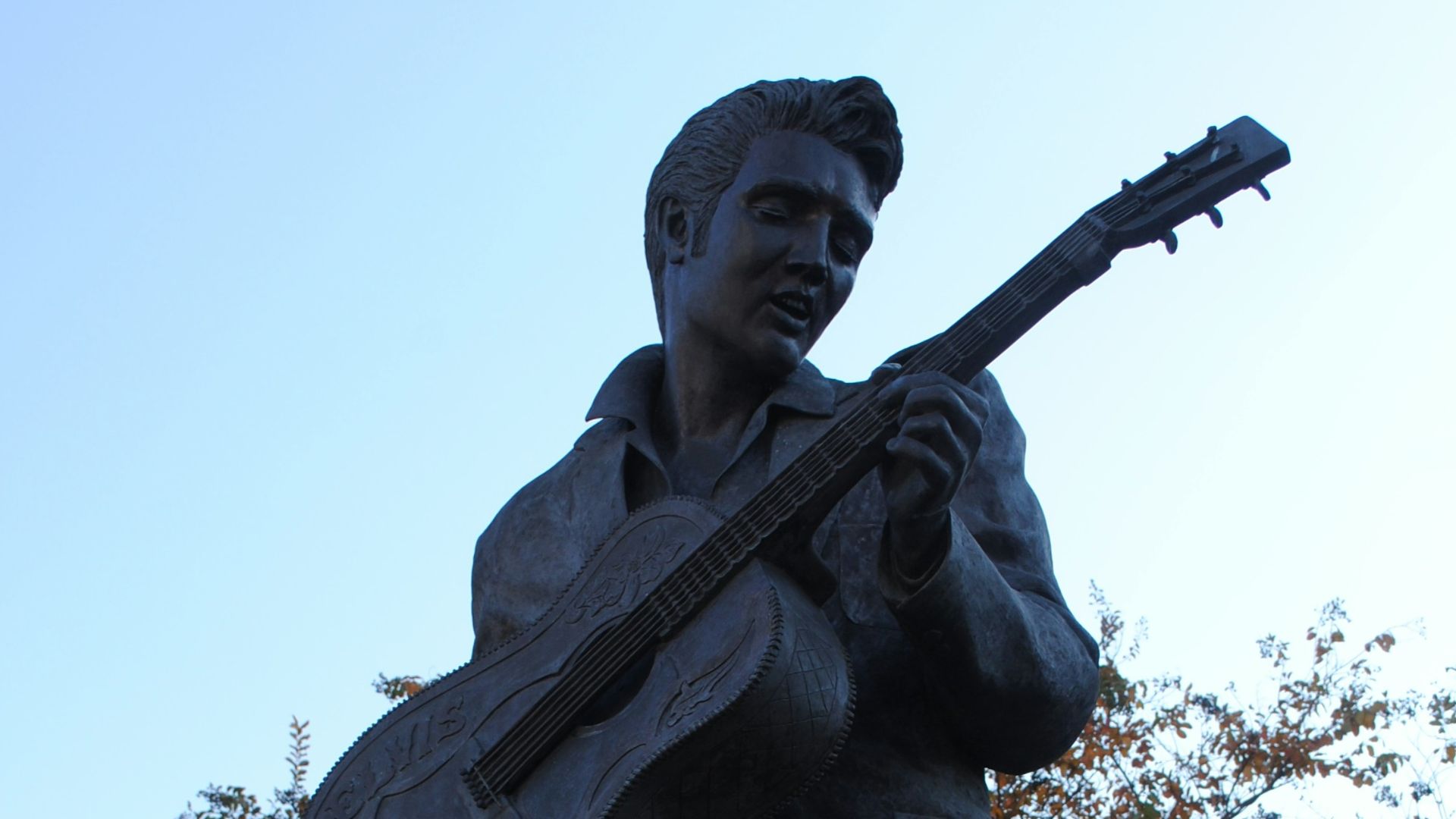 man holding stick statue under white sky during daytime