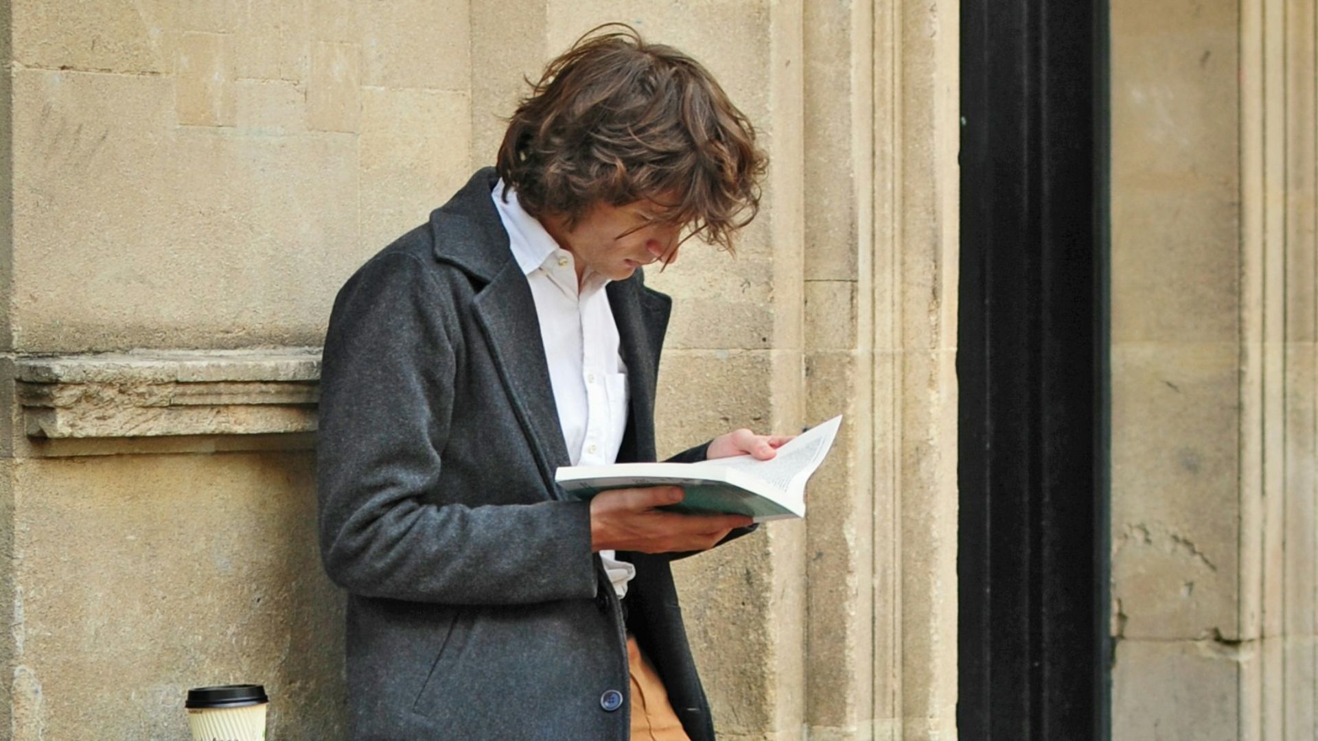 man sitting beside cup of coffee