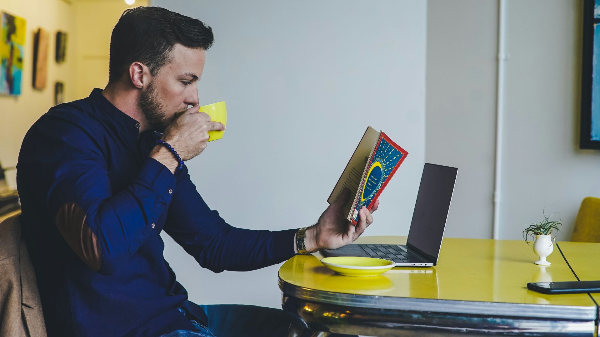 person reading book while drinking beverage