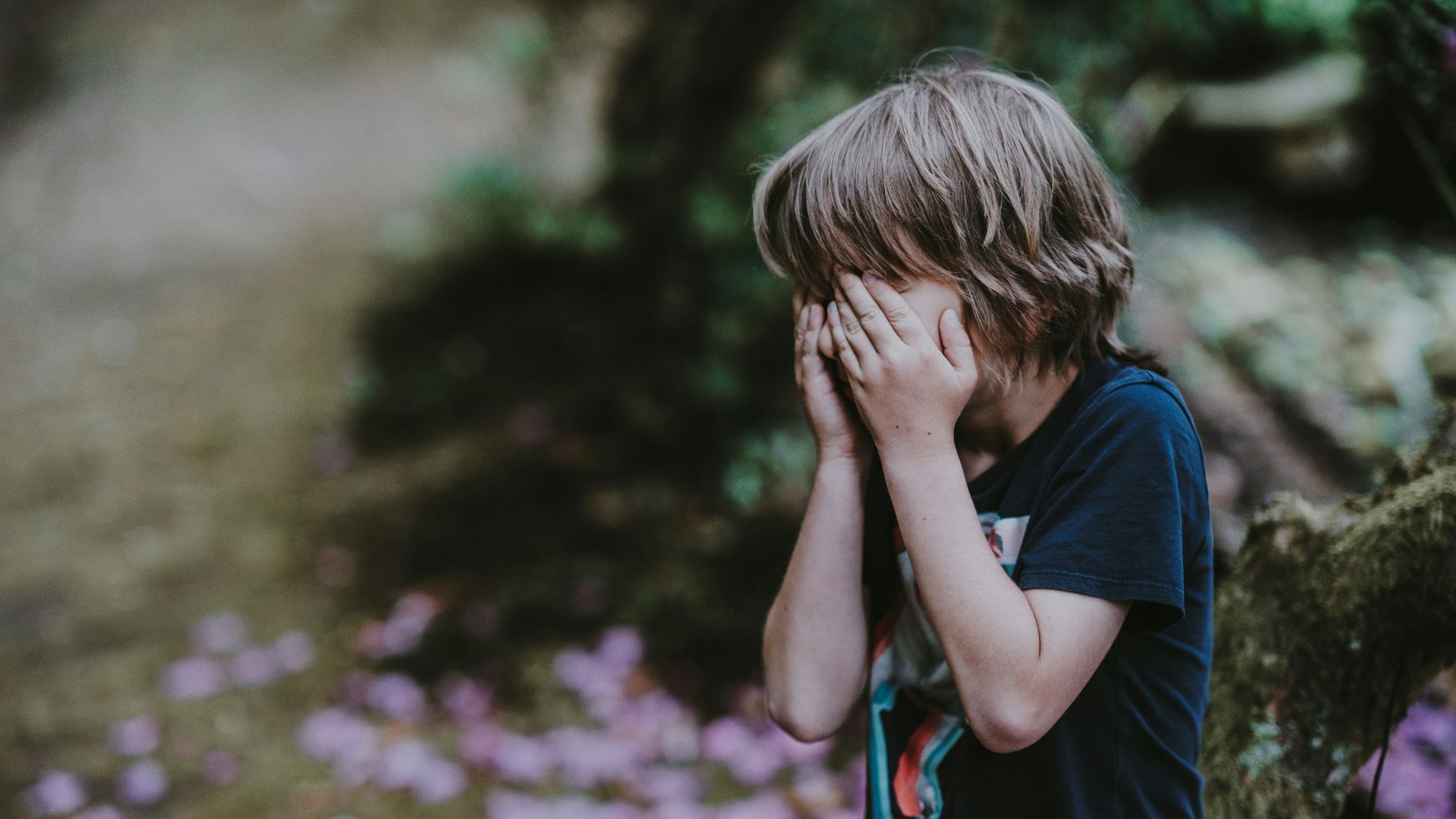 boy covering his face while standing