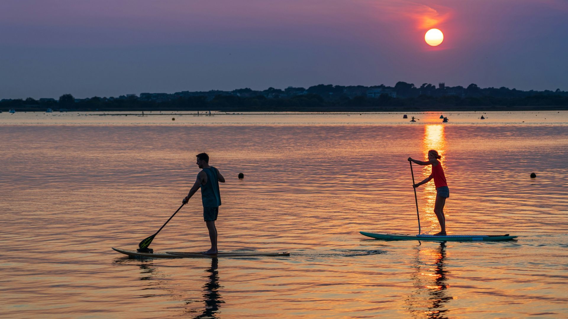man in black shirt and black shorts riding on boat during sunset