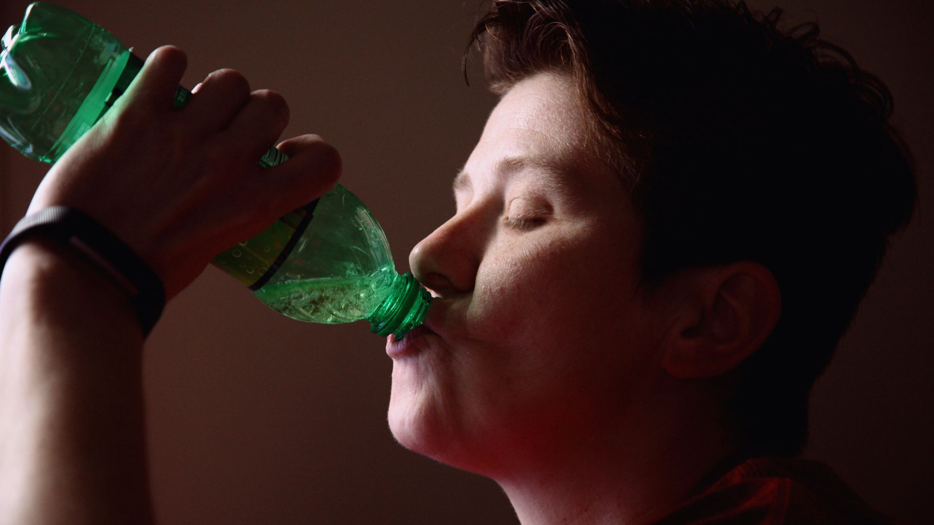 woman drinking from green plastic bottle