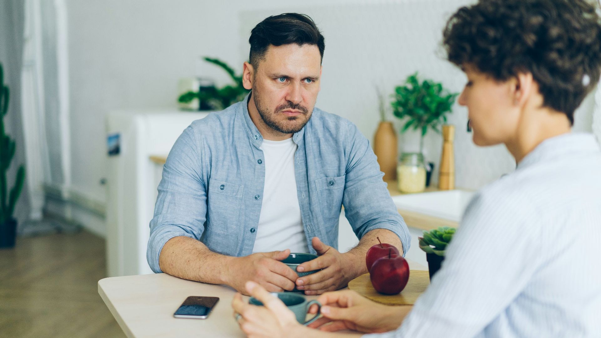 a man sitting at a table talking to a woman