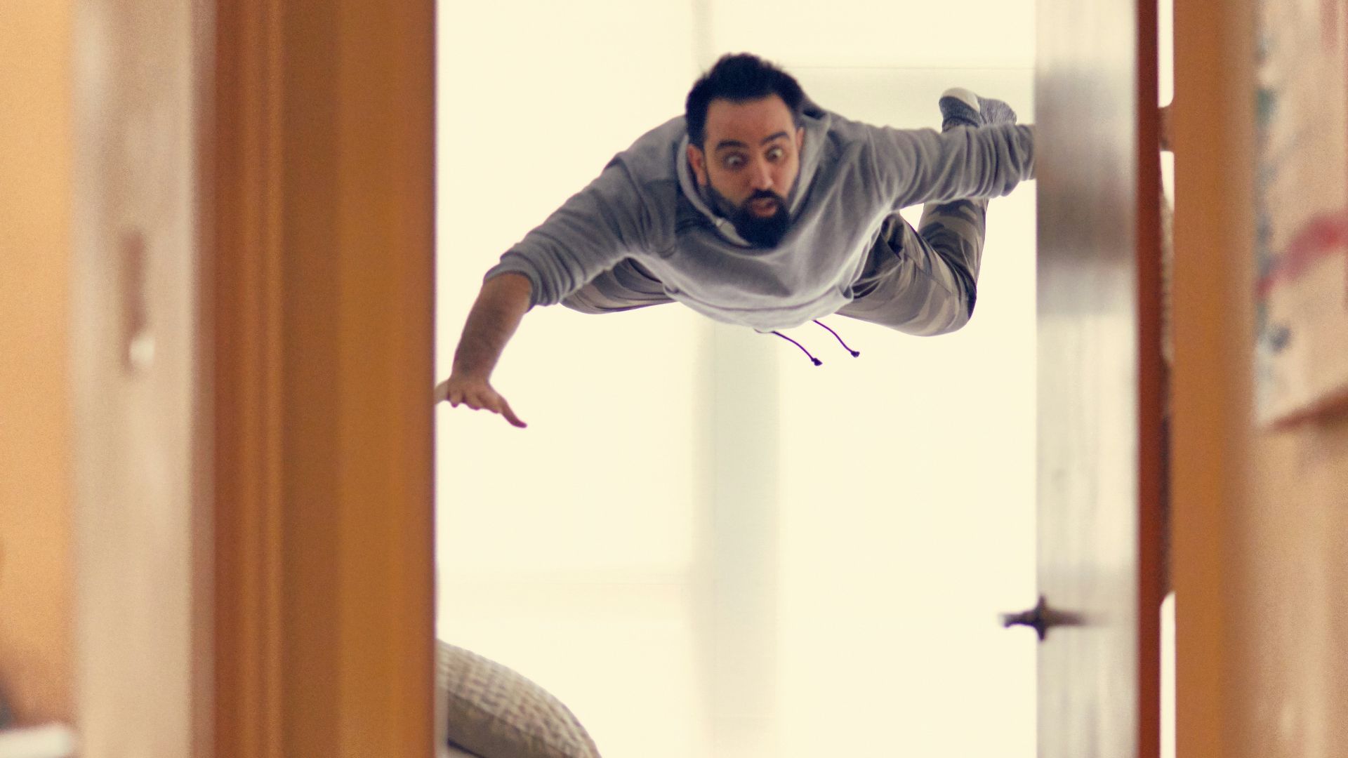 man falling from ceiling on bed