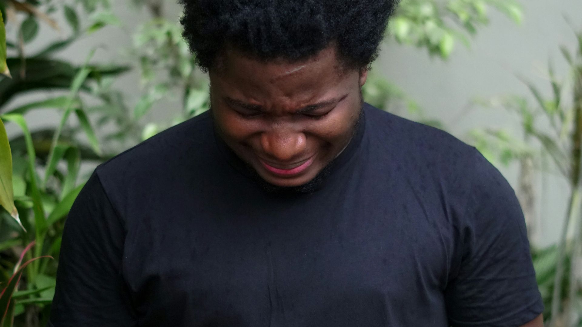 a man standing in front of a bush holding his hands together