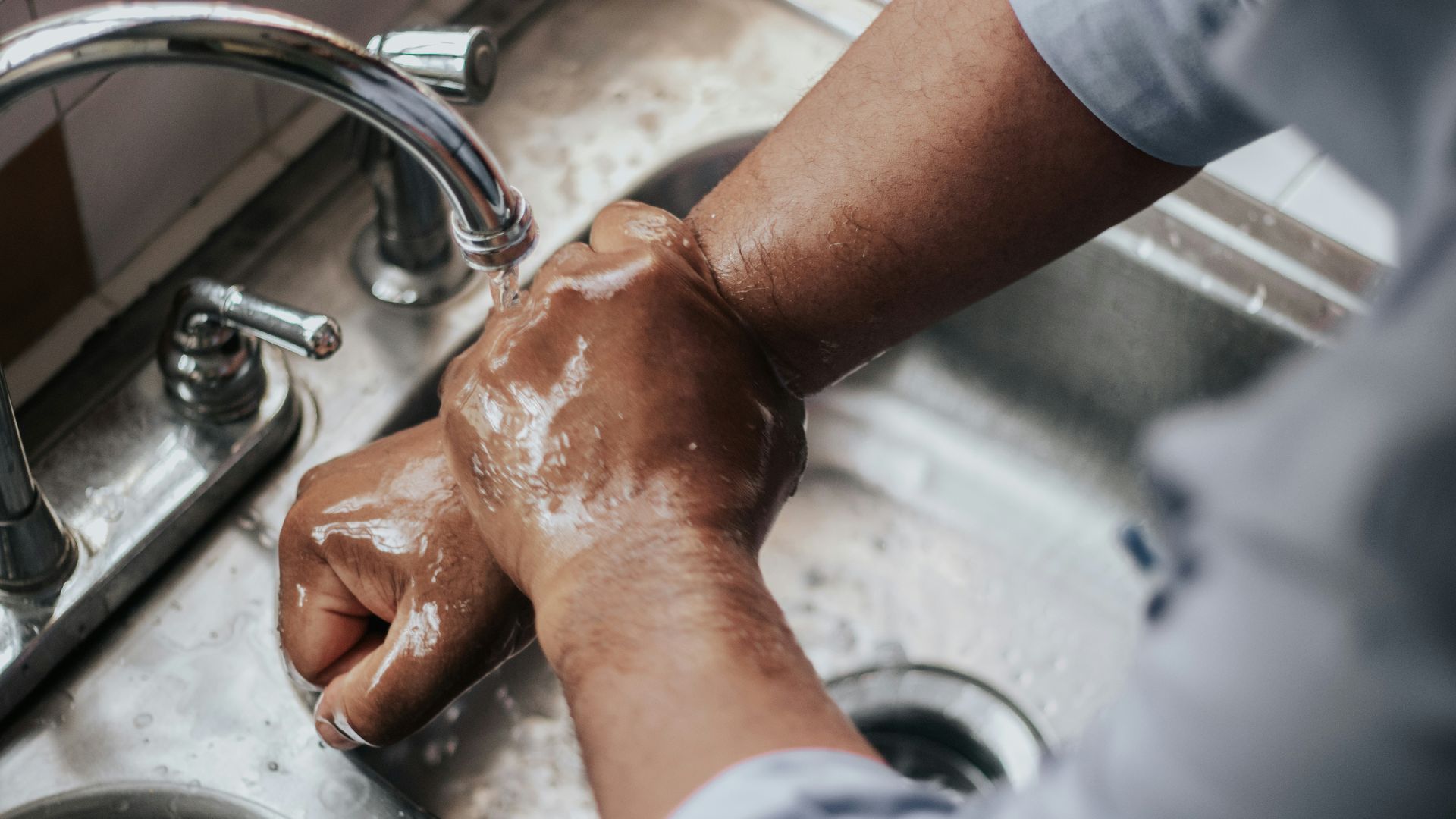 person in grey t-shirt washing hands