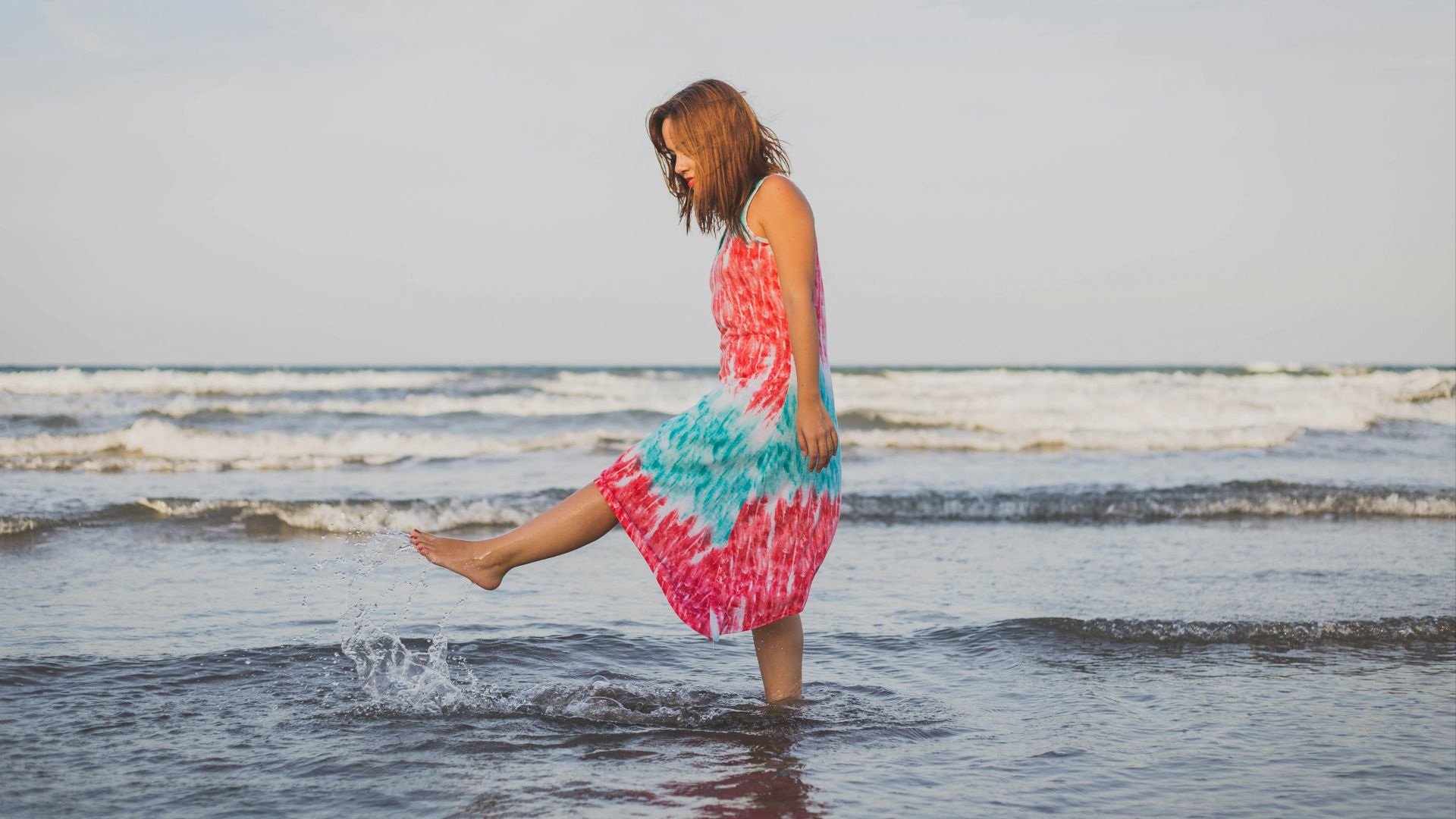 woman playing with water on shore during daytime