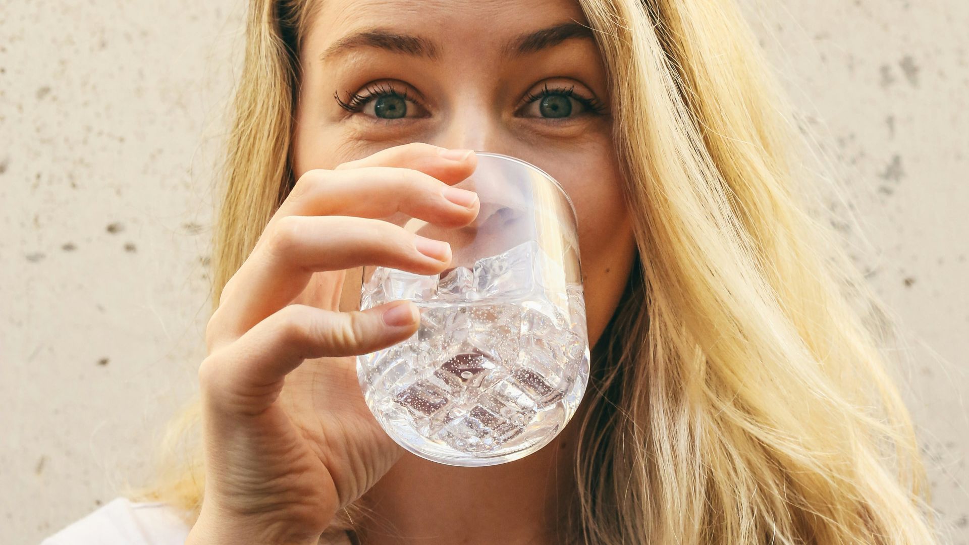 woman in white crew neck shirt drinking water