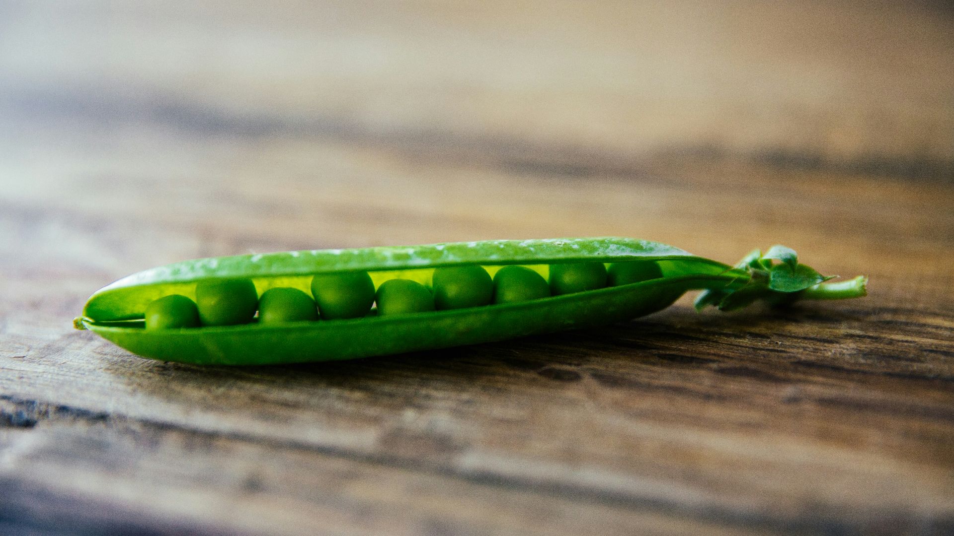 shallow focus photography of green pea on brown wooden surface