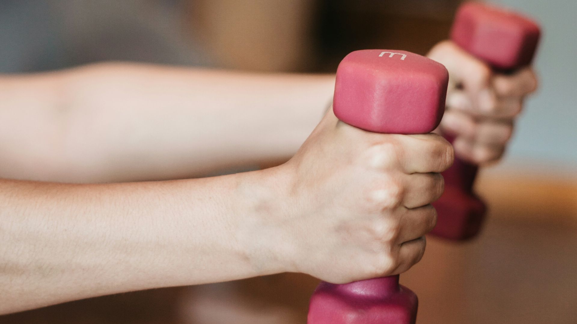 person holding pink and white dumbbells