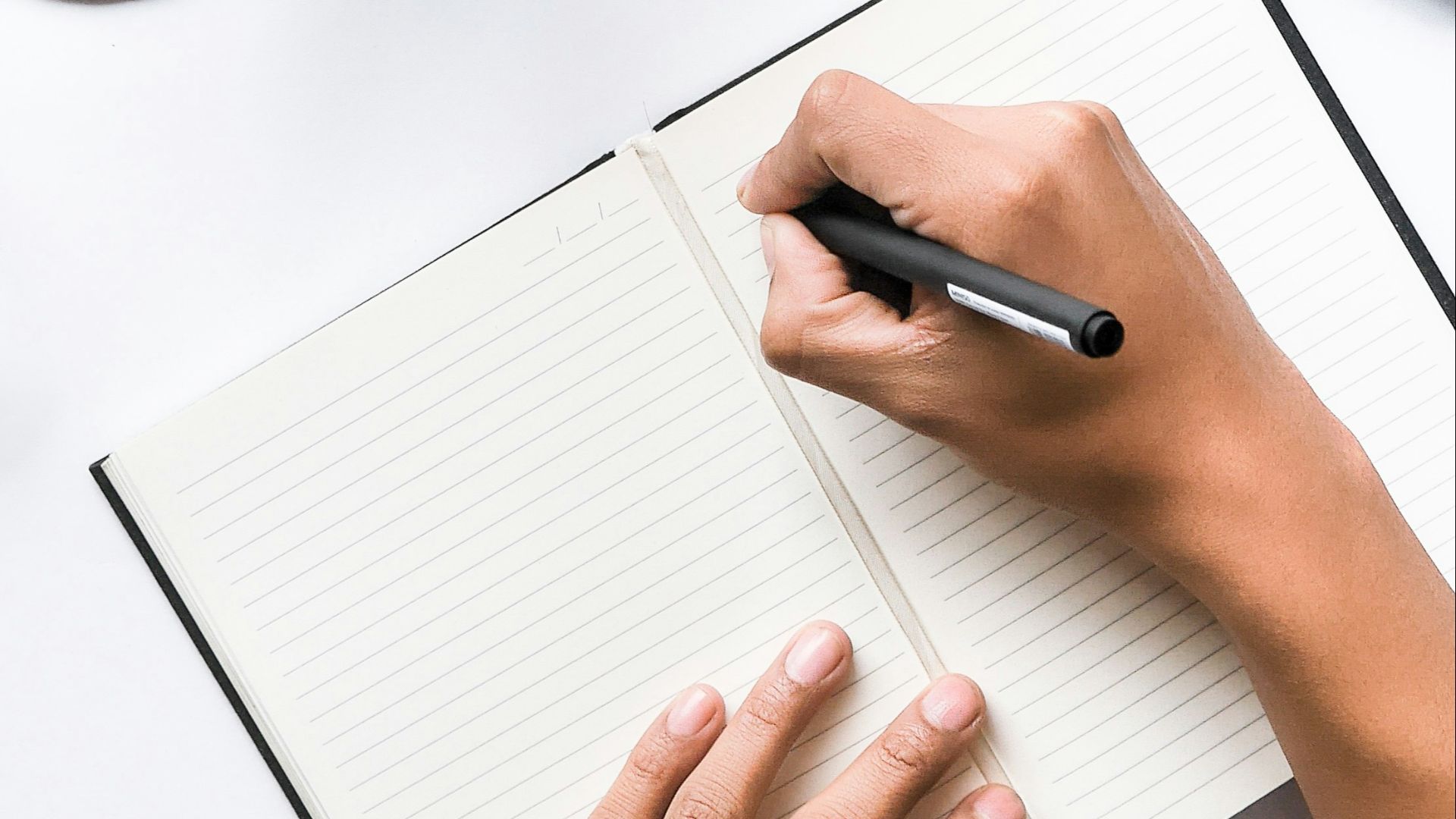 person writing on white notebook