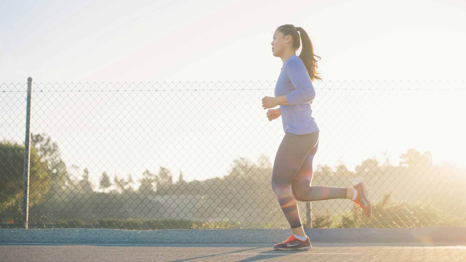 woman jogging near wire fence