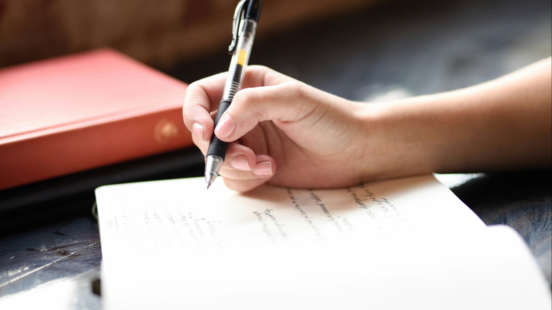 a person writing on a piece of paper with a pen