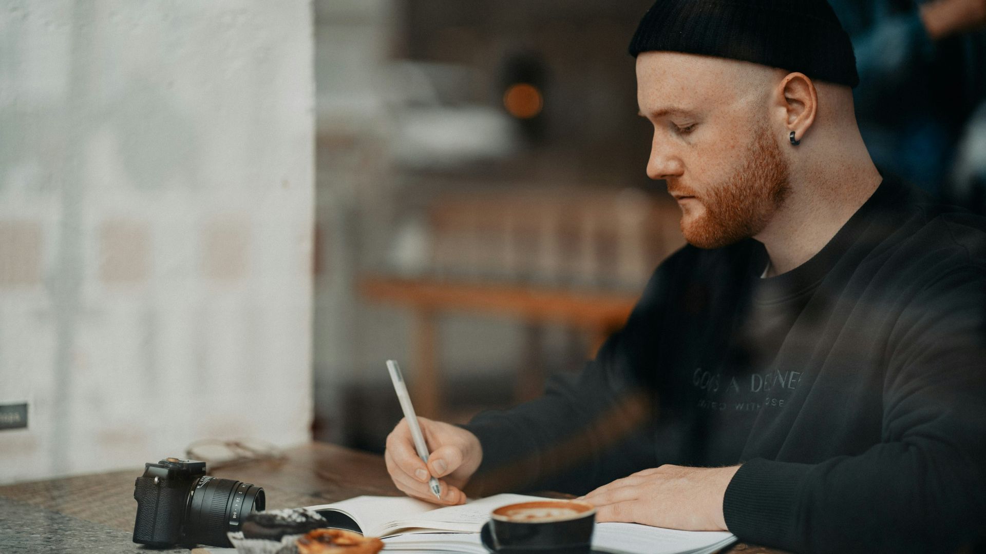 a man sitting at a table writing on a piece of paper