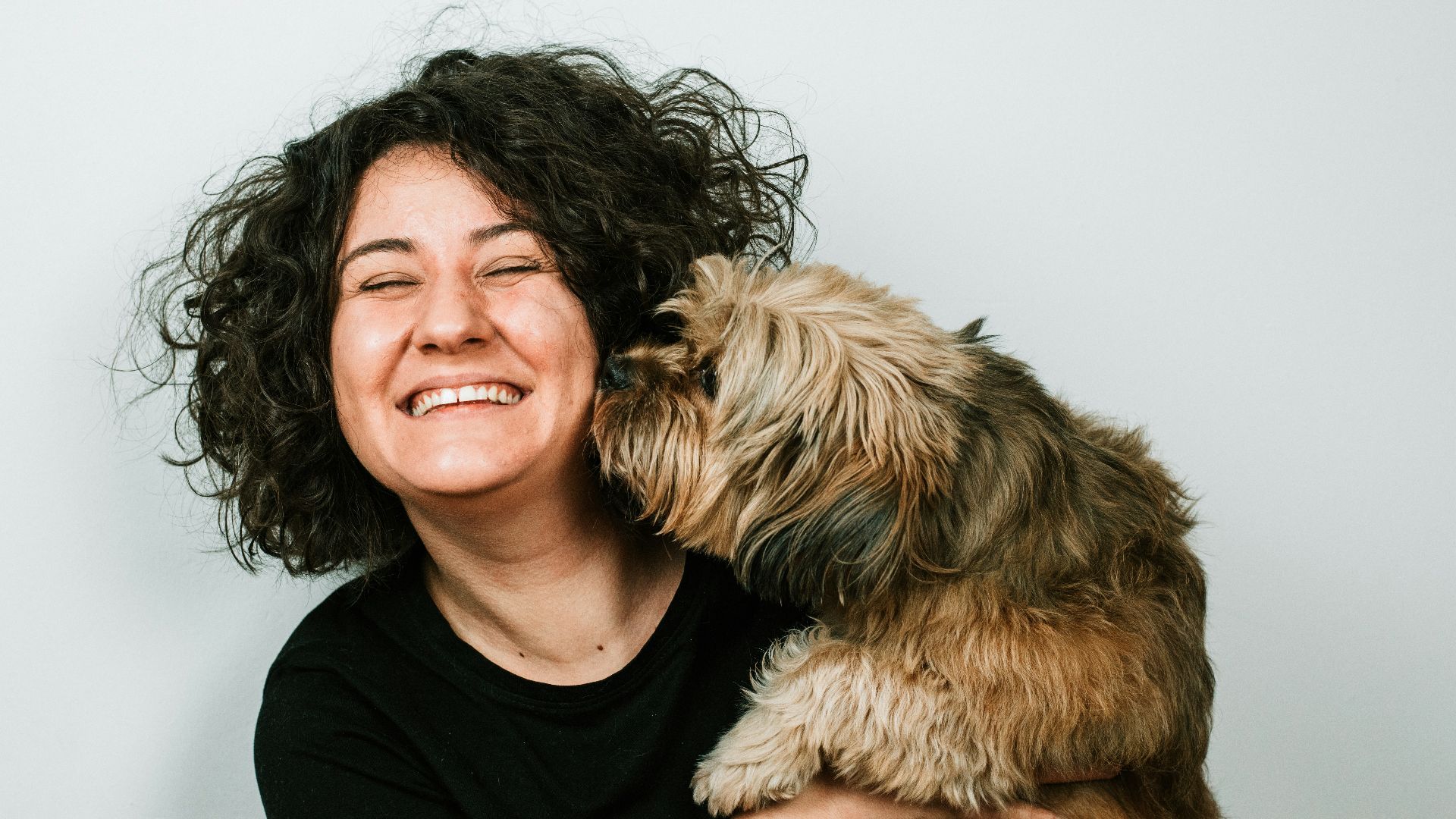 dog kissing woman in black crew-neck shirt