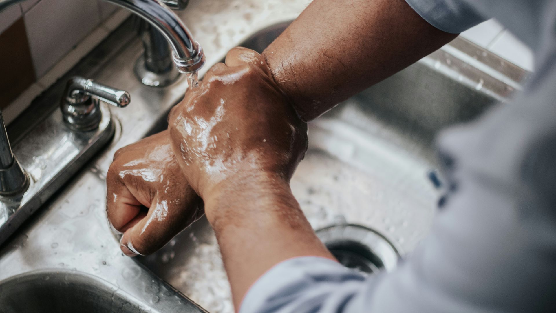 person in grey t-shirt washing hands