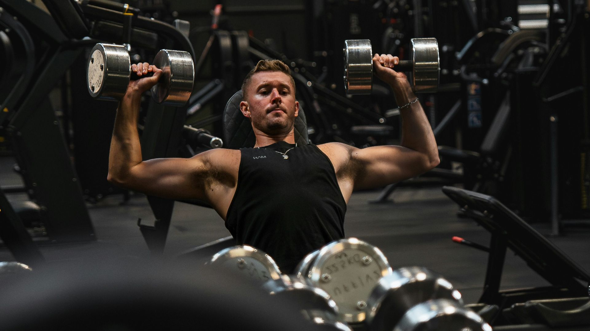 a man in a gym lifting a pair of dumbbells